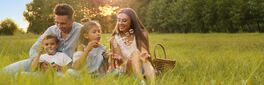 Happy family having picnic and blowing soap bubbles in park at sunset, space for text. Banner design Von New Africa