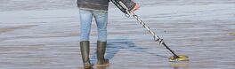 Mann mit Metallsuchgerät sucht bei Ebbe den Strand ab | Von JorGillwald