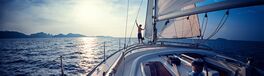 Young man standing on the yacht in the sea at sunset Von Dudarev Mikhail